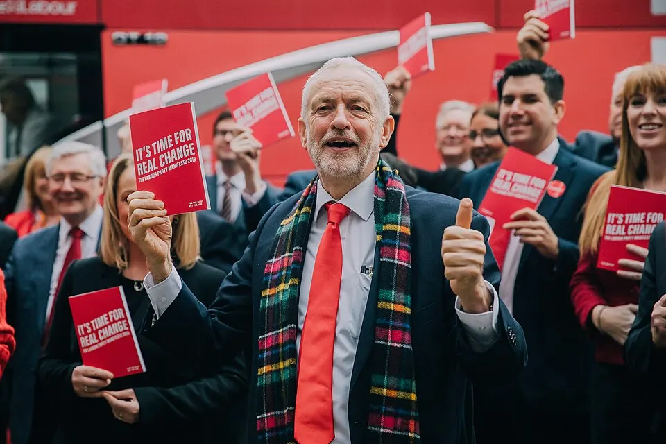 Jeremy Corbyn mostra il programma elettorale del Labour durante la presentazione a Birmingham, circondato da candidati e sostenitori